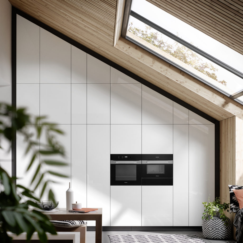 Cocina a medida con muebles en acabado blanco brillante y electrodomésticos en negro.