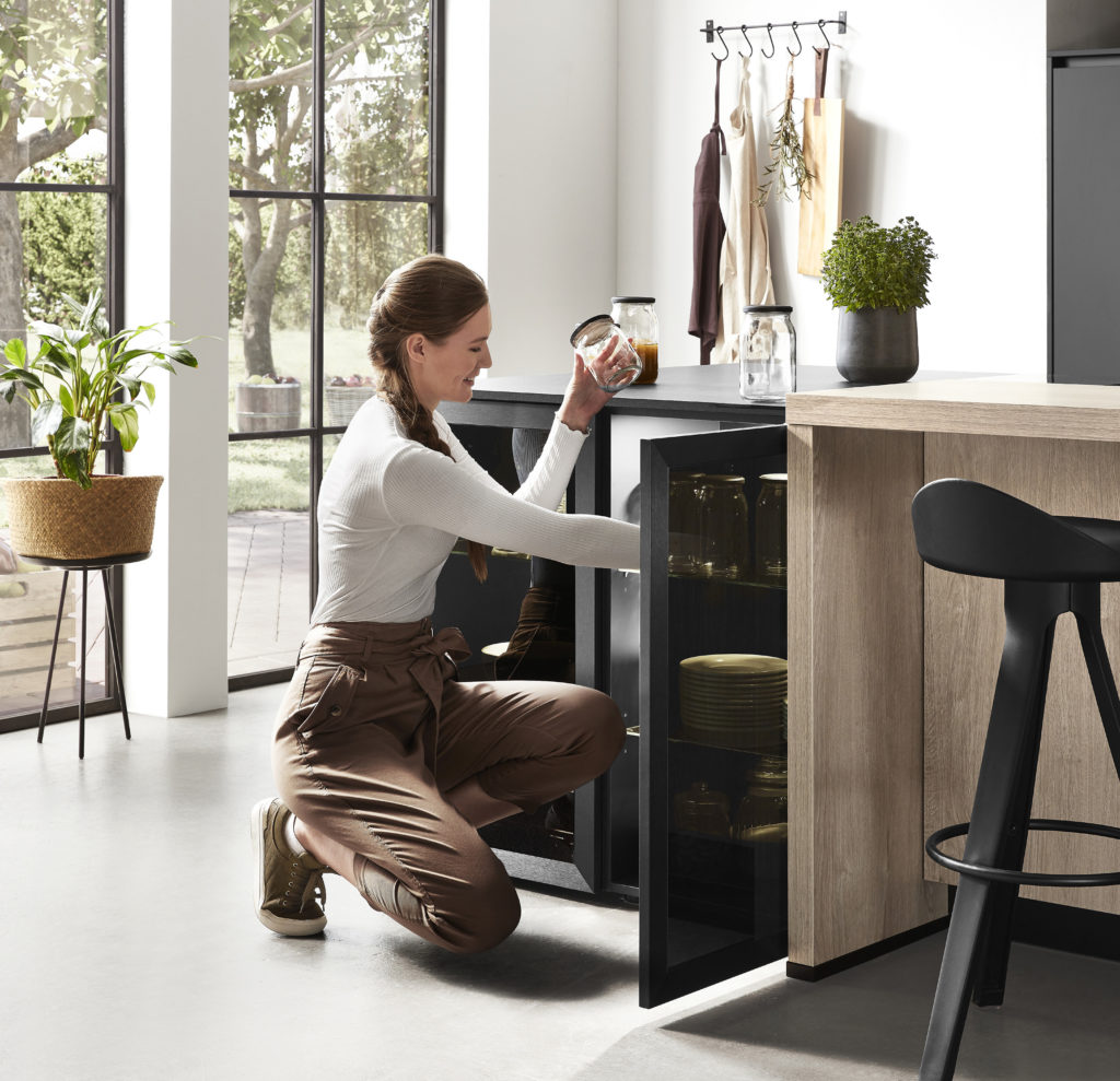 Chica joven ordenando armario de cocina