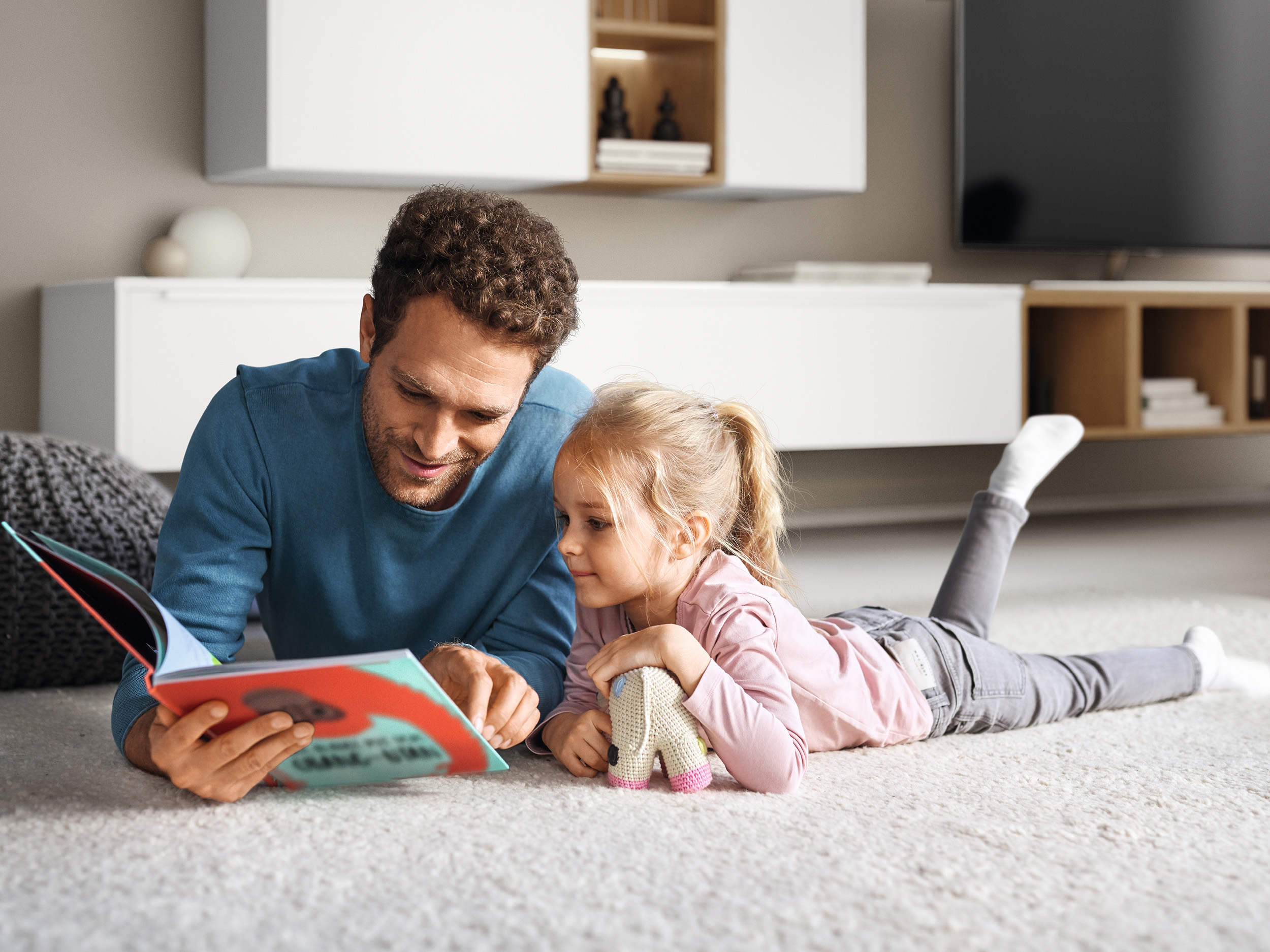 Padre e hija leyendo un libro en el salón